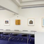 five works of art, all serigraphs, line a wall. The view is far, so the works appear to be predominantly red, grey, orange, black and white, and baby blue