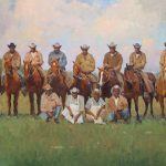 fourteen King Ranch staff face forward for this portrait. ten of the men are on tan horses all wearing beige cowboy hats except one which is black. four men kneel on the ground two in aprons