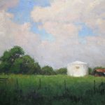 a scene of a lush green field and distant lush bushy green shrubs at the horizon with a white grain silo bearing the King Ranch running 