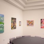 various colorful works of art hang on white walls